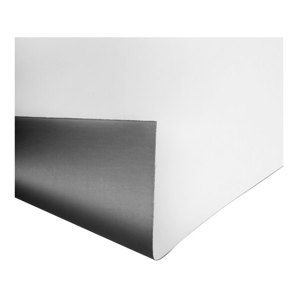 A close-up view of a flexible sheet with a white surface and a dark, magnet-like backing, partially curled at the corner.