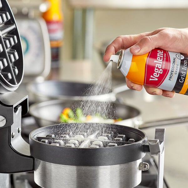 A hand spraying Vegalene Waffle-Off into a waffle iron.