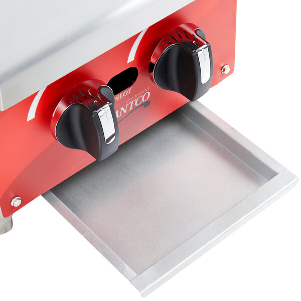An Avantco grease tray in a red and silver stove.