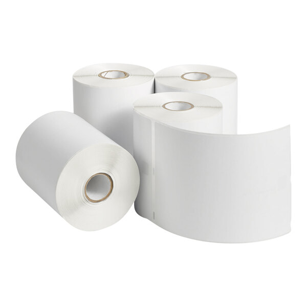 Four large rolls of blank white labels, with one roll partially unspooled to show the label surface.