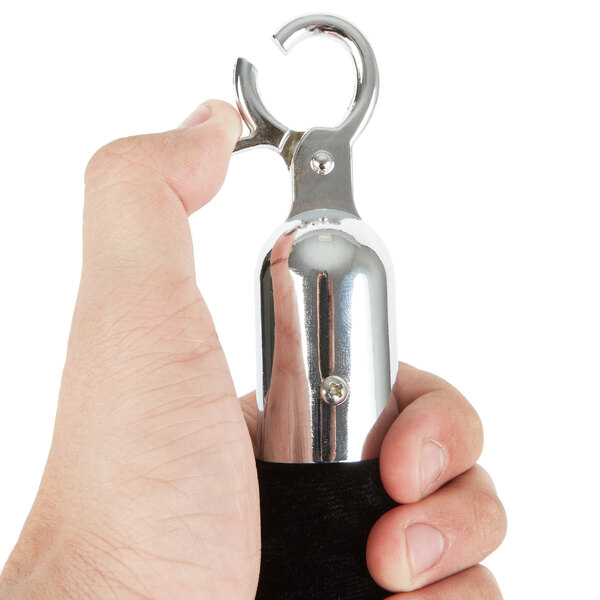 A hand holding a Lancaster Table & Seating black stanchion rope with silver ends.