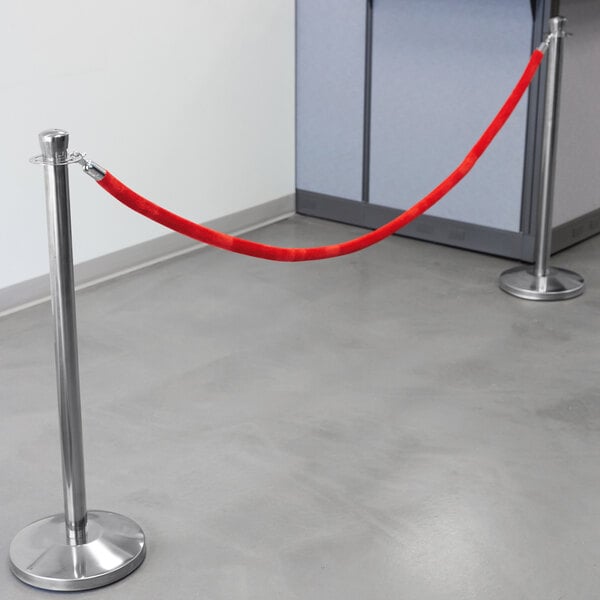 A Lancaster Table & Seating red rope tied to a silver stanchion pole.