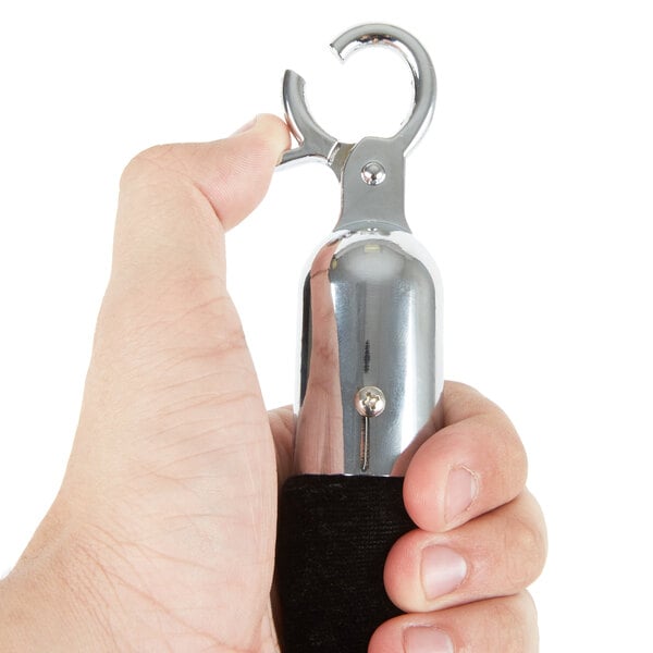 A hand holding a Lancaster Table & Seating black stanchion rope with silver ends.