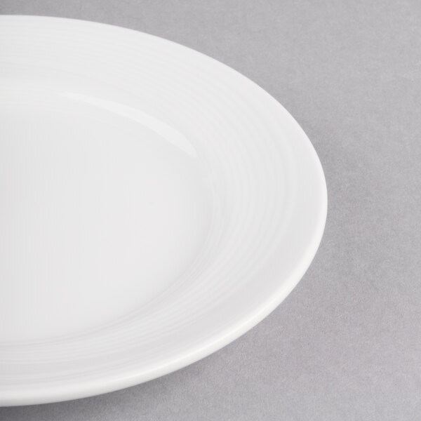 A close-up of a Reserve by Libbey Royal Rideau white porcelain plate with a white rim.