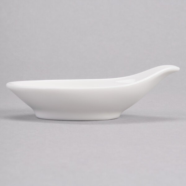 A white Royal Rideau porcelain bowl with a curved handle and a spoon on top.