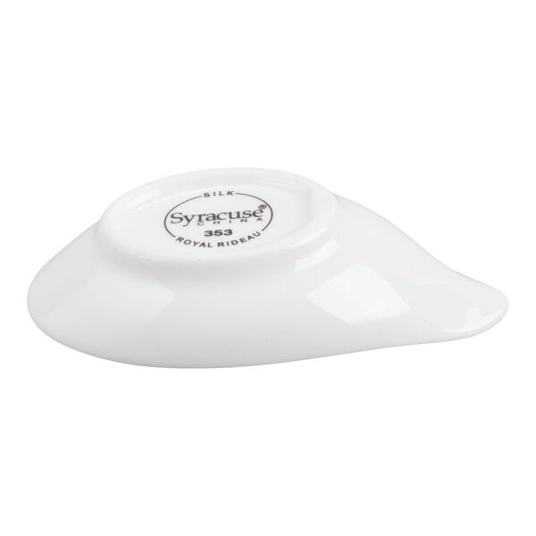 A small, white, glossy porcelain dish with a rounded base and a slightly pointed end, shown upside down with a manufacturer's mark on the bottom.