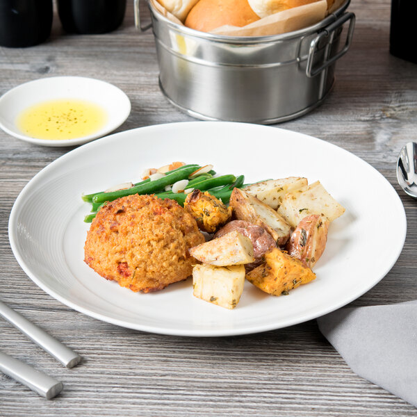 A Reserve by Libbey white porcelain coupe plate with a meal of potatoes, carrots, and green beans on a table.