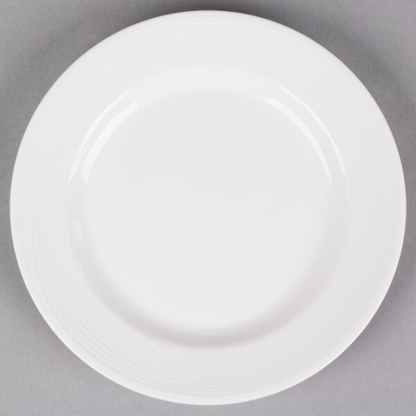 A white Reserve by Libbey porcelain plate with a wide rim on a gray surface.