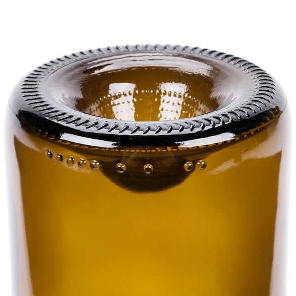 An Arcoroc amber glass wine tumbler with a metal rim on a table in a winery.