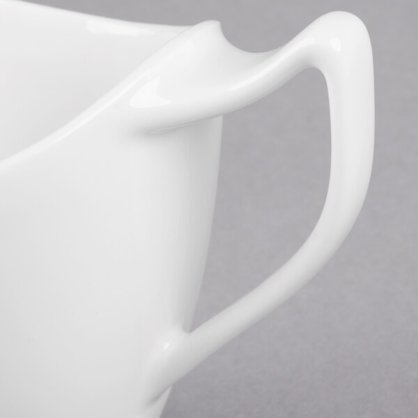 A close-up of a white pitcher with a handle.