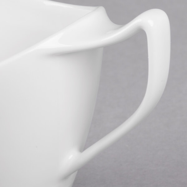 A close-up of a white Royal Rideau porcelain creamer with a handle.