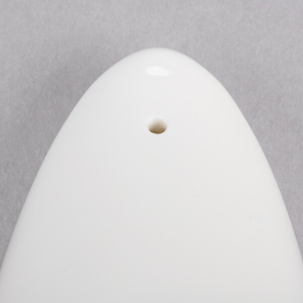 A white porcelain pepper shaker with a hole in it.