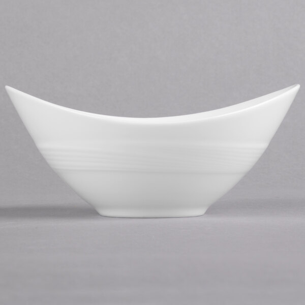 A close-up of a white Reserve by Libbey Silk oval bowl with a curved edge.
