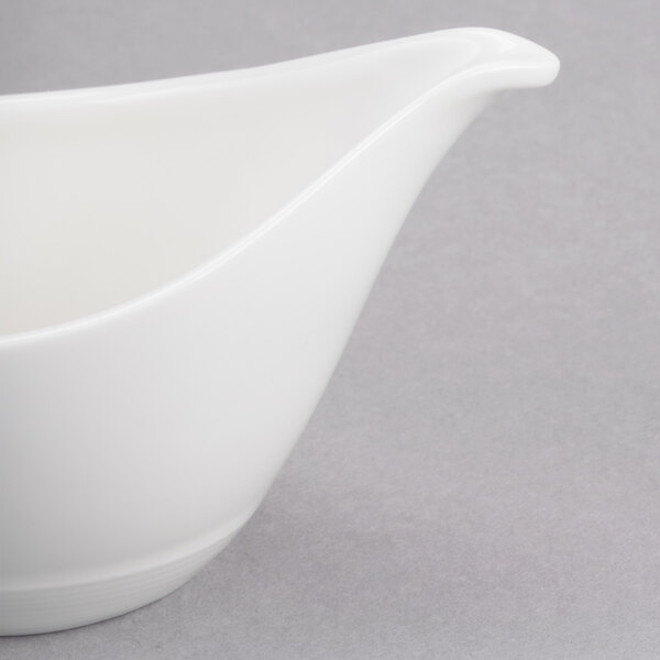 A close-up of a white Reserve by Libbey Royal Rideau porcelain sauce boat.