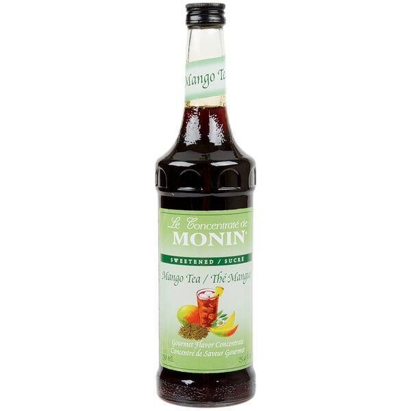 A close-up of a Monin Mango Tea Concentrate bottle with a label.