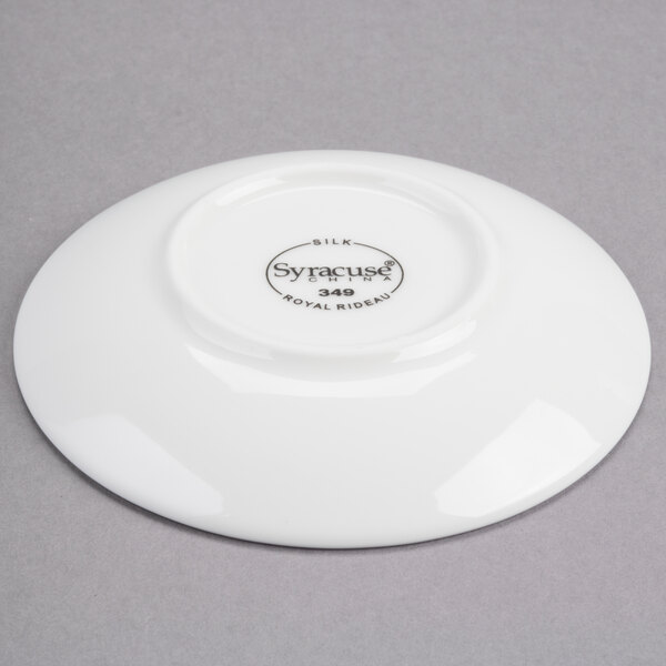 A white porcelain round dipping dish with a small black logo.