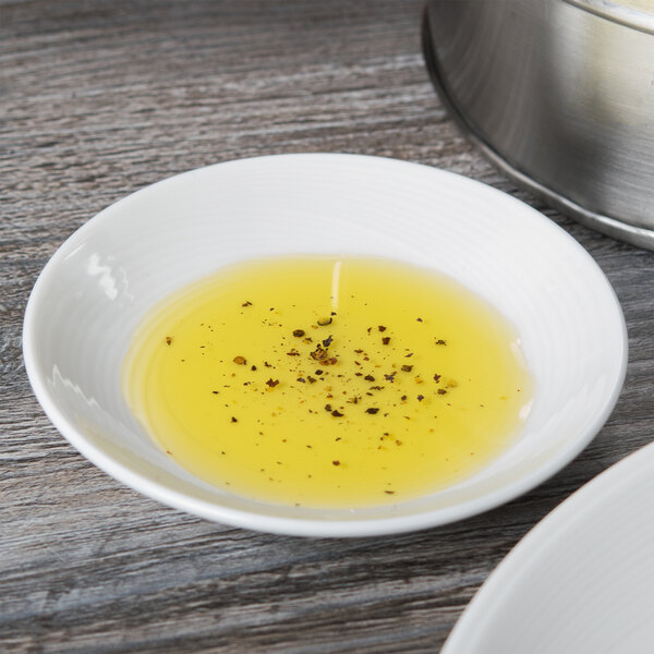 A Reserve by Libbey white porcelain dipping dish filled with olive oil and spices next to a bowl of rice.