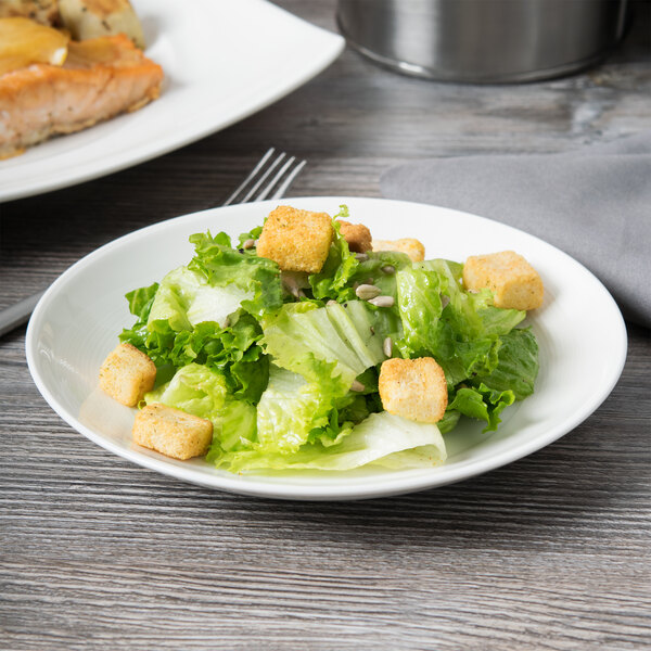 A white Reserve by Libbey Royal Rideau coupe plate with a salad on it.