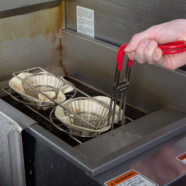 A hand using a Tablecraft tortilla fry basket to fry tortillas.
