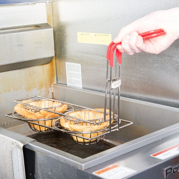 A hand using Tablecraft tortilla double taco fry baskets in a deep fryer.