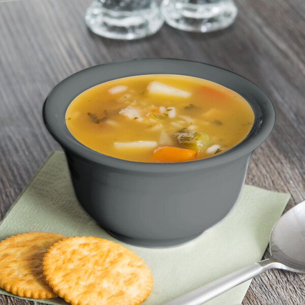 A Fiesta Slate China bouillon bowl filled with soup and crackers on a napkin.