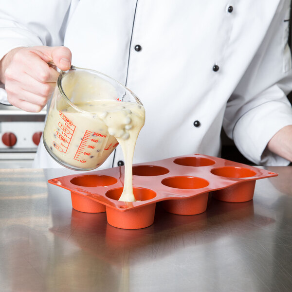 A chef pouring batter into a Matfer Bourgeat muffin pan.