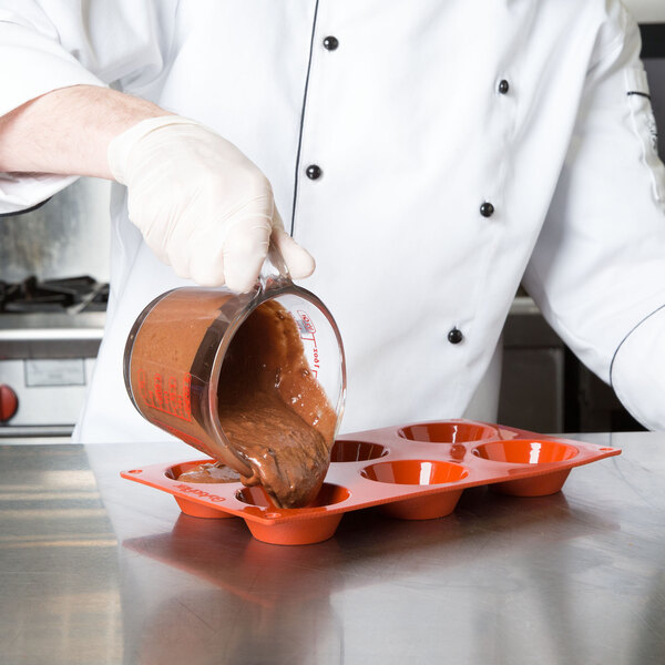 A chef pouring brown liquid into a Matfer Bourgeat silicone dessert mold.