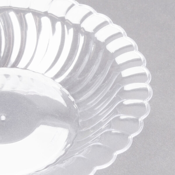 A clear plastic Fineline Flairware bowl with a scalloped edge.