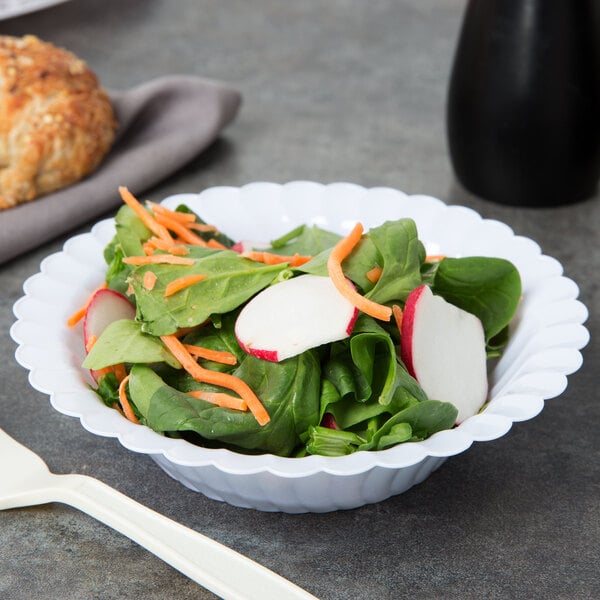 A Fineline white plastic bowl filled with salad and vegetables, including carrots.