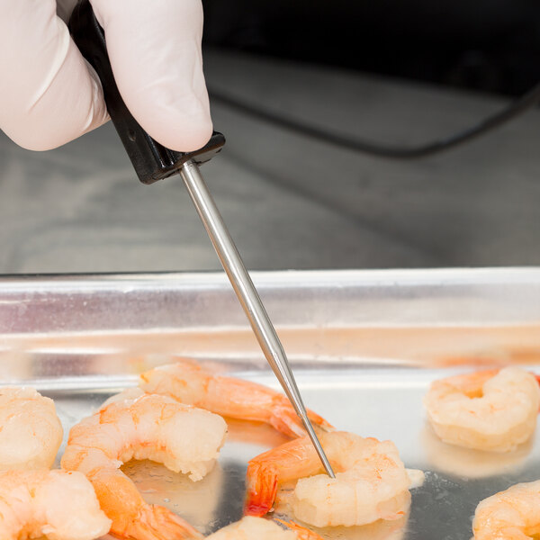 A person using a Cooper-Atkins AquaTuff Thermocouple Thermometer to check the temperature of shrimp.