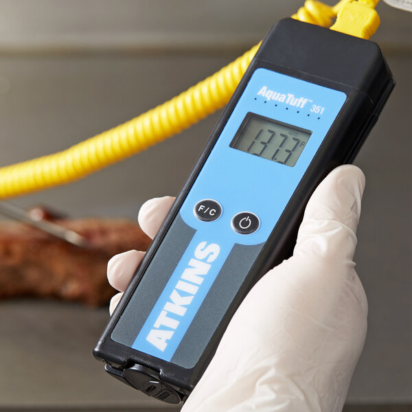 A person holding a Cooper-Atkins AquaTuff Type-K Thermocouple Thermometer.