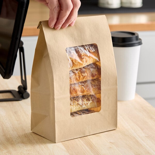 A brown kraft paper bag with a clear window displaying pastries inside.