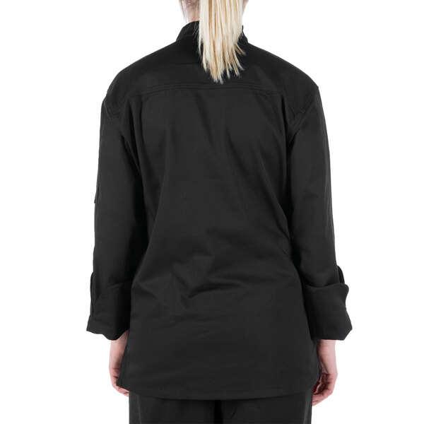 A woman wearing a black Mercer Culinary long sleeve chef jacket.