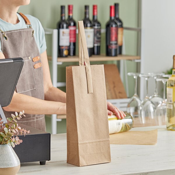 A woman in an apron standing behind a counter with a brown kraft paper wine bag with bottles of wine inside.