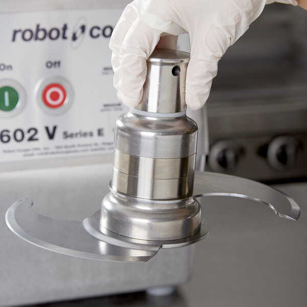 A hand in a white glove installing the Robot Coupe 27124 Smooth "S" Blade.