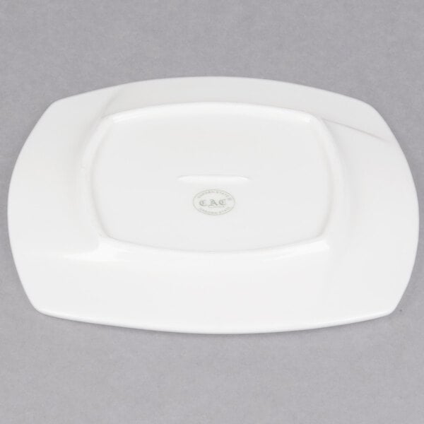 A CAC white porcelain square plate on a gray surface.