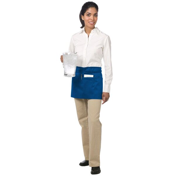 A woman wearing a white shirt and a royal blue Chef Revival waist apron holding a glass of ice.