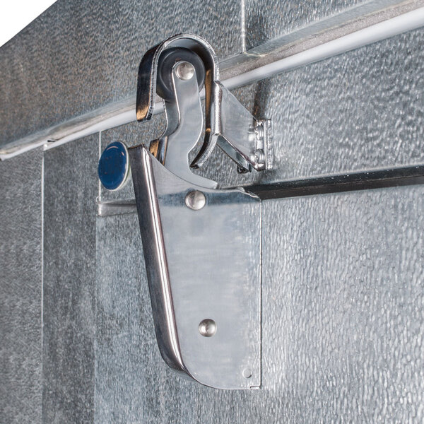 A metal latch mechanism attached to the door of an outdoor walk-in freezer.