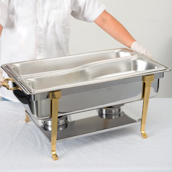 A person in a white coat using a Vollrath adapter bar to hold a silver container in a chafer.