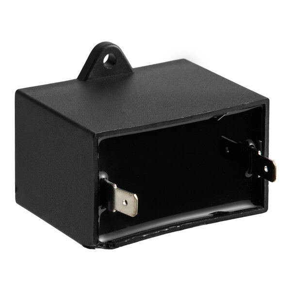 A black rectangular electronic component with two metal prongs and a mounting tab, likely a capacitor.