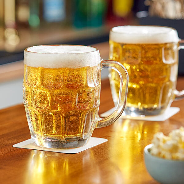 Two Libbey glass mugs of beer on a table.