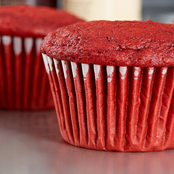 A close-up of a red velvet cupcake in a Hoffmaster white fluted baking cup.