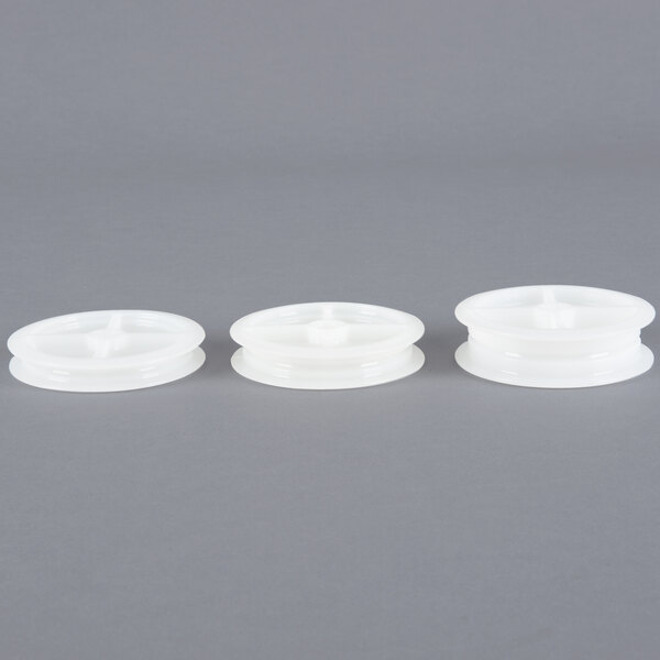 Three white plastic spools with round tops.