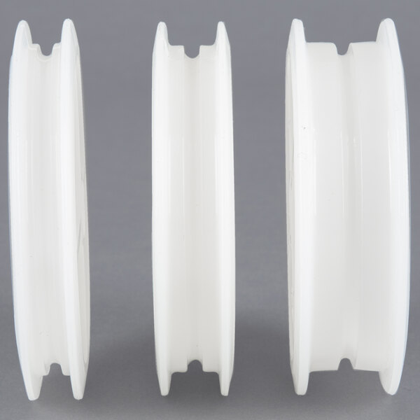 Three white plastic spools in a white container with a black lid.