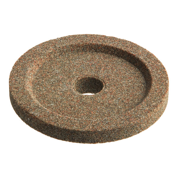 A brown circular sharpening stone with a hole in the middle.