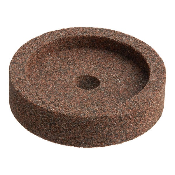 A round, coarse-textured sharpening stone with a central hole.
