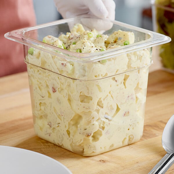 A person holding a clear plastic container of food.