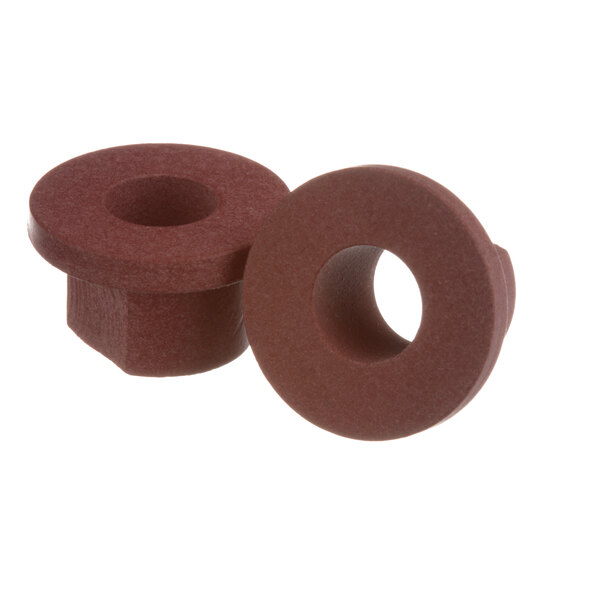 A close-up of a pair of brown rubber bushings with a dark center.