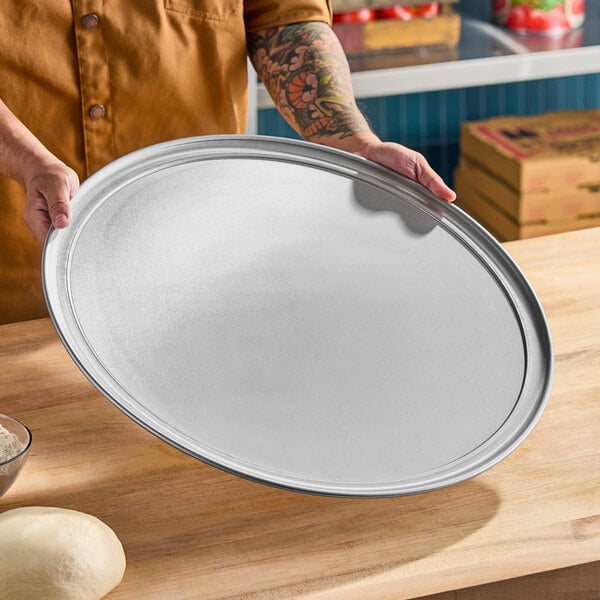 A large, round, heavy weight aluminum pizza pan with a wide rim.