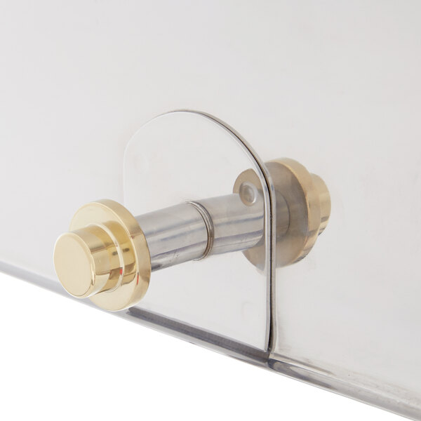 A close-up of a clear and gold metal Vollrath New York Chafer cover handle.